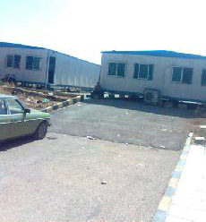 طلبة في كلية الحصن يتلقون دروسهم واقفين وآخرون يحملون مقاعدهم بين المحاضرات