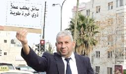 خمسيني يبحث عن عمل بالوقوف ورفع لافتة قرب تقاطع أم أذينة